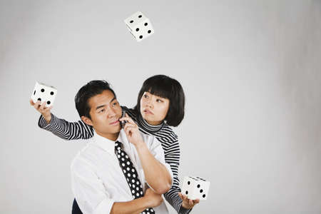 Asian woman juggling dice over manの写真素材