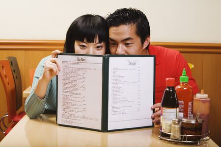 Asian couple reading menu at restaurantの写真素材