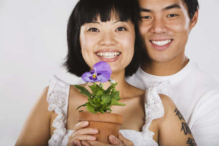 Portrait of Asian couple holding potted plantの写真素材