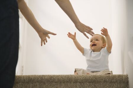 Crying baby reaching for motherの写真素材