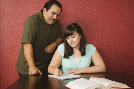 Hispanic father helping daughter with homeworkの写真素材