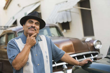 Middle-aged Hispanic man in front of classic carの写真素材