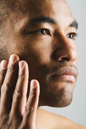 Close up of Asian man touching faceの写真素材