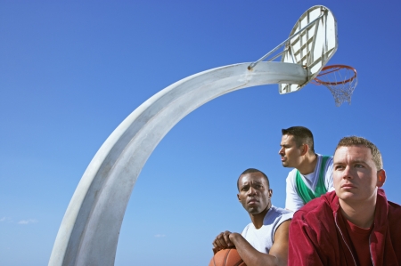 Multi-ethnic men under basketball hoopの写真素材