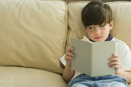 Greek boy reading on sofaの写真素材
