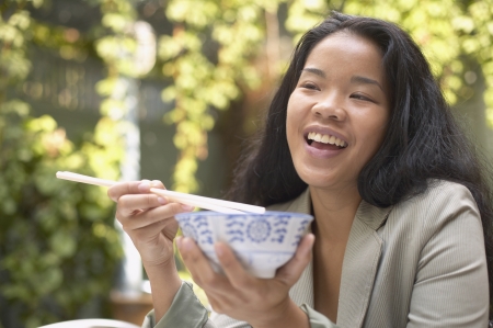 Asian woman eating with chopsticksの写真素材