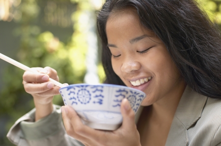 Asian woman eating with chopsticksの写真素材