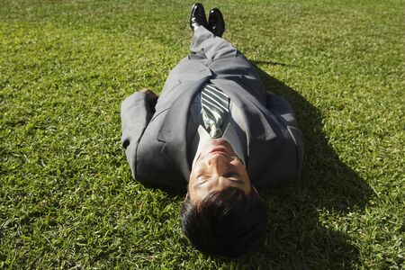 South American businessman laying in grassの写真素材