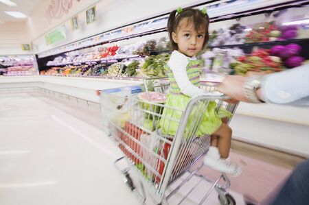Hispanic girl in shopping cartの写真素材