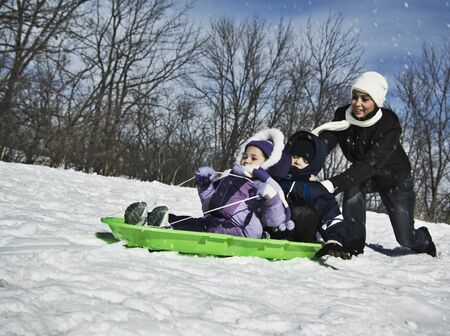 Mother pushing children on sledの写真素材