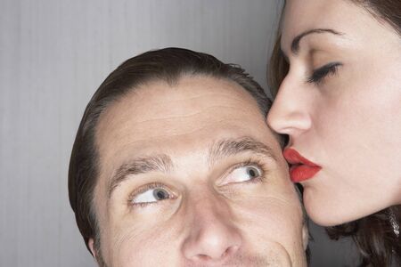 Woman kissing man on templeの写真素材