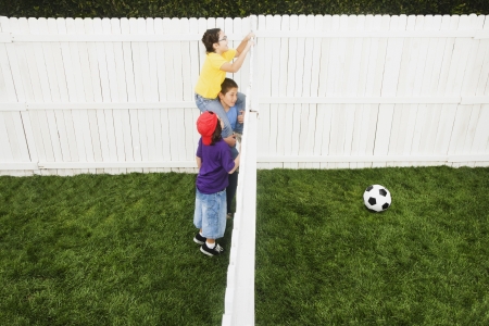 Mixed Race children looking over fence at soccer ballの写真素材