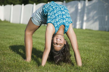 Hispanic girl doing back bend on grassの写真素材