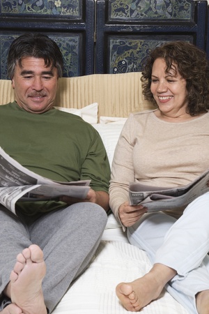 Senior Hispanic couple reading newspaperの写真素材