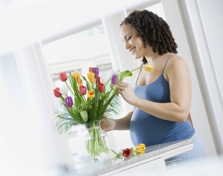 Pregnant African woman arranging flowersの写真素材