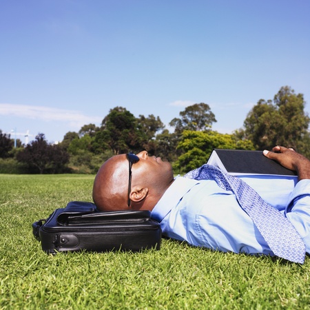 African businessman laying in grassの写真素材