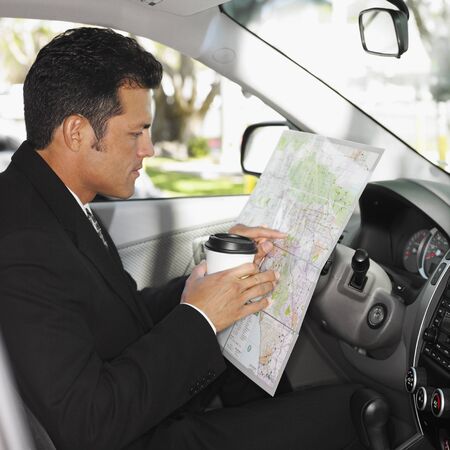 Hispanic man reading map in car