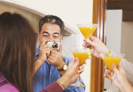 Middle-aged Hispanic man taking photograph of friendsの写真素材