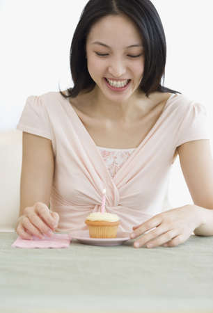 Asian woman and candle on cupcakeの写真素材