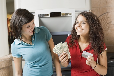 Multi-ethnic teenage girls holding money and credit cardの写真素材