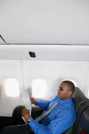 Mid adult businessman traveling in an airplaneの写真素材