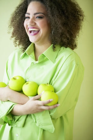 Mid adult woman smiling holding applesの写真素材