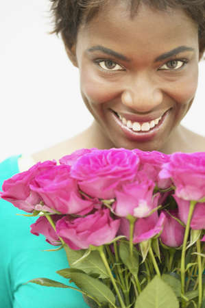 Young woman standing holding a bouquet of roses smilingの写真素材