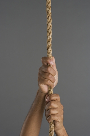 Close up of two hands hanging on ropeの写真素材