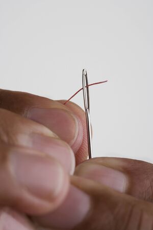Close up of hands threading needleの写真素材