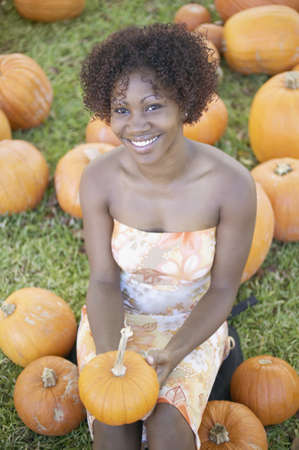 Portrait of woman sitting in pumpkin fieldの写真素材