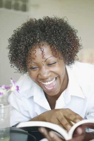 Woman laughing and reading bookの写真素材