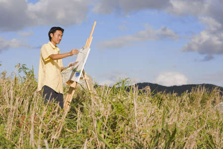 Asian man painting at easel outdoors, Florianopolis, Brazilの写真素材