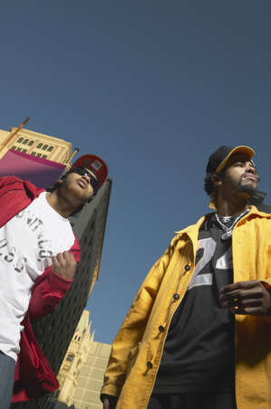 Low angle view of two young African men standing in urban area, Oakland, California, United Statesの写真素材