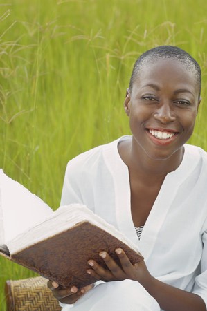 African American woman reading book outdoors