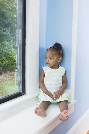 Young African girl sitting in window seatの写真素材