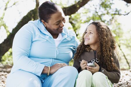 African mother and daughter smiling at each other outdoorsの写真素材