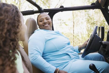African mother and daughter sitting in jeep smiling