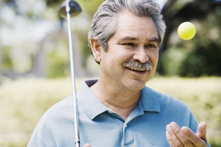 Middle-aged man with golf club and golf ballの写真素材