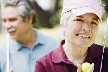 Middle-aged couple with golf clubsの写真素材