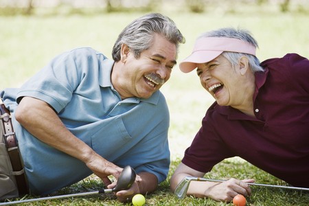 Middle-aged couple laughing with golf clubsの写真素材