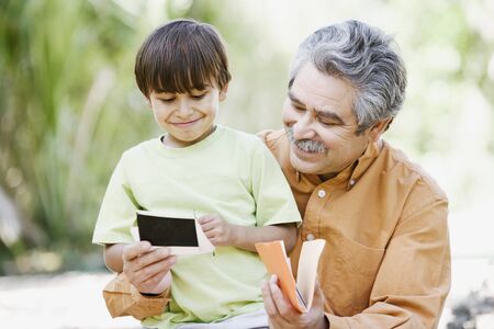 Father and son looking at photographs outdoorsの写真素材