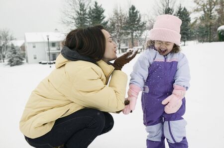 Mother and young daughter playing with snow