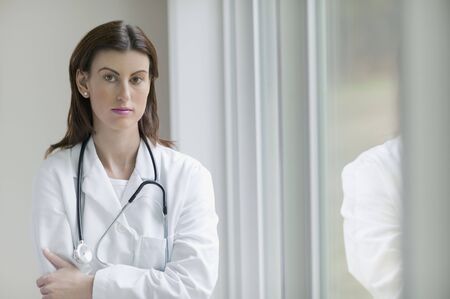 Female doctor standing next to window indoorsの写真素材