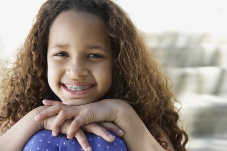 African girl with braces leaning chin on knees outdoorsの写真素材