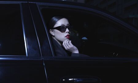 Asian woman sitting in car wearing sunglassesの写真素材