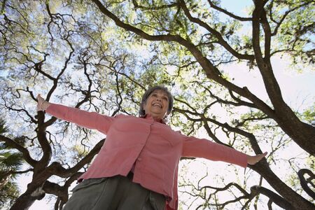 Low angle view of senior woman with arm outstretched outdoors