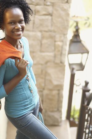 Young African woman with jacket over shoulder smilingの写真素材