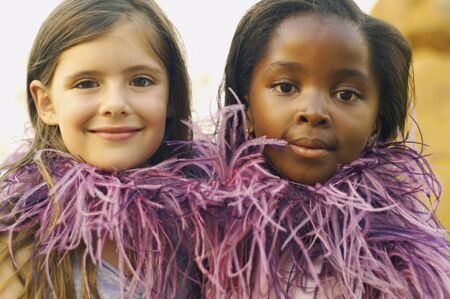 Two young girls wearing feather boa and smilingの写真素材