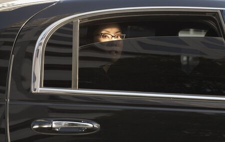 Asian woman in limousine with window part of the way downの写真素材