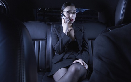 Asian businesswoman using cell phone in back seat of carの写真素材